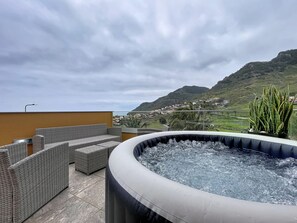 Eine Dachterrasse mit Korbmöbeln und einem Whirlpool.