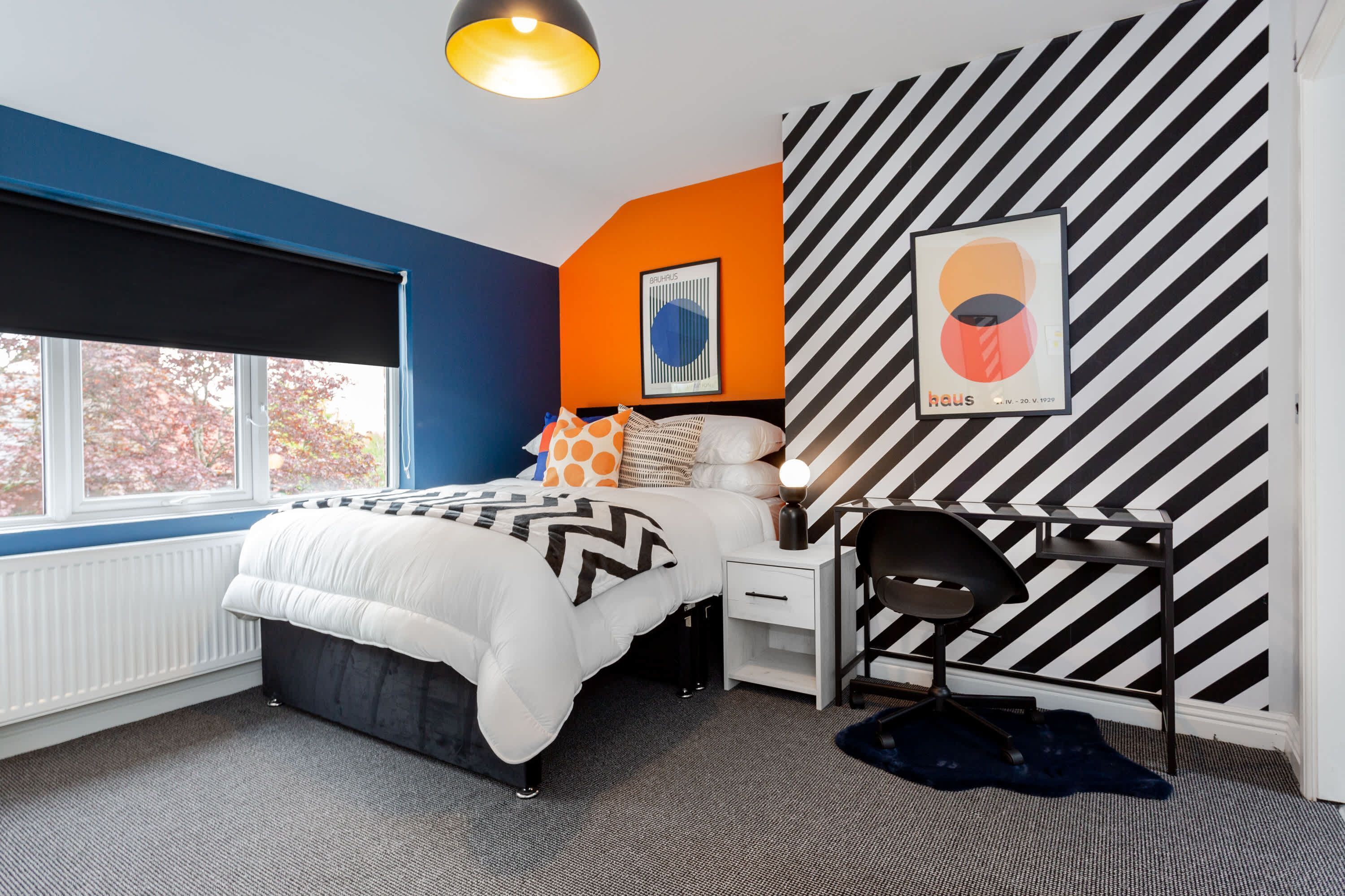 A bedroom with a bed, bedside table, chair, and a window with a view.