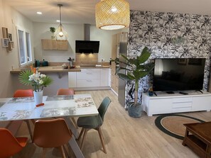 A modern kitchen with a TV, dining table, chairs, and a large plant. - Jungle - Air-conditioned 4* apartment with terrace and mountain views (DRUMETTAZ CLARAFOND)