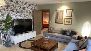 A living room with a TV, sofa, coffee table, and decorative items.