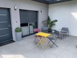 A modern outdoor patio with a yellow table and chairs, a potted plant, and a sliding door. - Jungle - Air-conditioned 4* apartment with terrace and mountain views (DRUMETTAZ CLARAFOND)