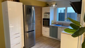 A modern kitchen with a stainless steel refrigerator, wooden cabinets, a microwave, and a window with a view.