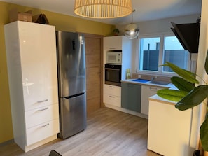 A modern kitchen with a stainless steel refrigerator, wooden cabinets, a microwave, and a window with a view. - Havana - Air-conditioned 4* apartment with terrace and private garden (DRUMETTAZ CLARAFOND)