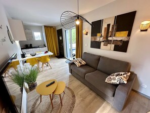 Un salon moderne avec un canapé, une table basse et un coin repas avec des chaises jaunes.