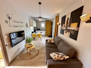 A modern living room with a sofa, TV, and artwork. - Yellow Cab - Air-conditioned 3* apartment with terrace and mountain views (DRUMETTAZ CLARAFOND)