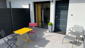 Un patio con un tavolo giallo, due sedie, una panca rossa e una pianta in vaso.