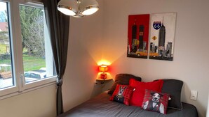 Una camera da letto con un letto, una lampada, una finestra e una parete con un segnale stradale.