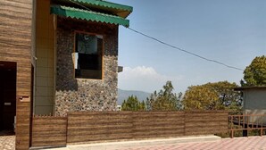 A building with a stone facade, a wooden door, and a checkered pavement in front. - Pine Peak Kasauli (Kasauli)