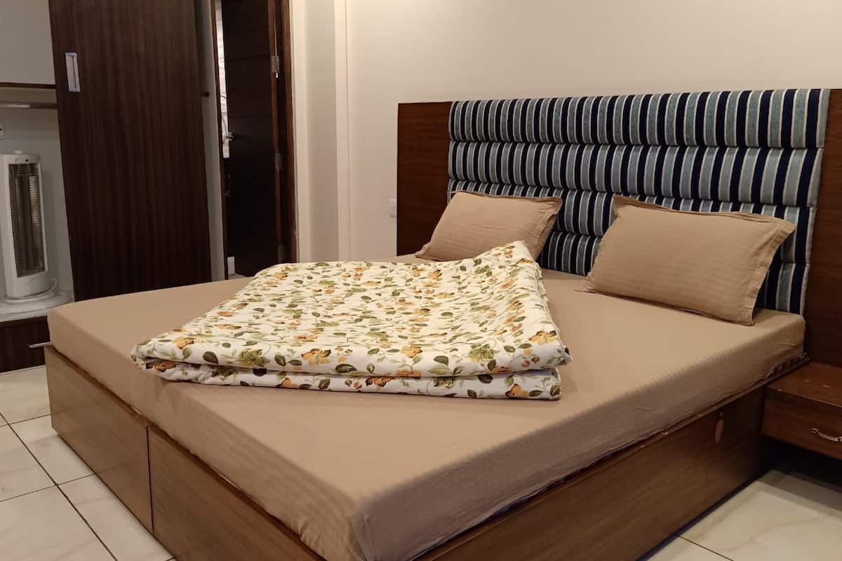 Una cama con colcha estampada, cabecera a rayas y mesita de noche de madera.