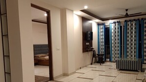 A spacious room with a tiled floor, a bed, a small table, and curtains. - Pine Peak Kasauli (Kasauli)