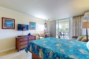 Ein Schlafzimmer mit Bett, Fernseher, Schreibtisch und Balkon.