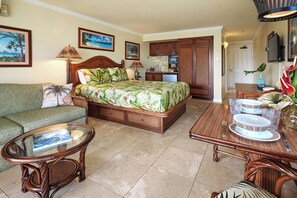 A hotel room with a bed, a sofa, a dining table, and a kitchen area.