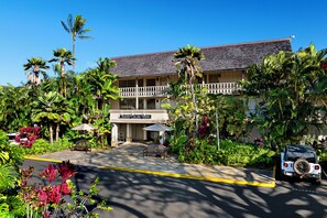 A hotel with a two-story building, a covered entrance, and a parking area with a vehicle.