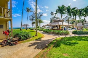 Ein Resort mit einem Pfad, der zu einem strohgedeckten Gebäude führt, umgeben von Palmen und einem gepflegten Rasen.