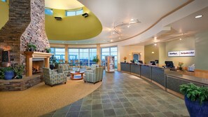 A spacious lobby with a stone fireplace, comfortable seating, a reception desk, and large windows offering a view. - Beachfront WorldMark Seaside Stay with Pools, Space & Family Fun by the Ocean (Seaside)