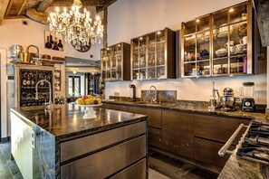 A modern kitchen with a central island, built-in cabinets, a chandelier, and a wine rack.