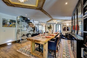 Un comedor con una mesa de madera larga, sillas y un tapete estampado.