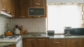 Una cocina con armarios de madera, estufa a gas, microondas y cafetera.