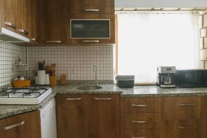 Une cuisine avec des meubles en bois, une cuisinière à gaz, un four à micro-ondes et une machine à café.