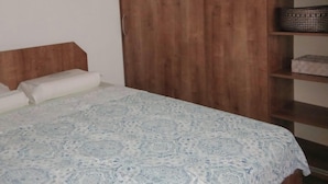 Un dormitorio con una cama, un armario de madera y una estantería.