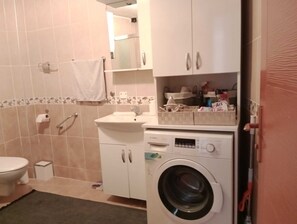 Ein Badezimmer mit Toilette, Waschbecken, Waschmaschine und Spiegel.