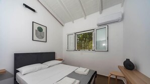 A modern bedroom with a bed, bedside tables, a window with a view, and a wall-mounted air conditioner. - Mary's Country House (Lefkimmi)
