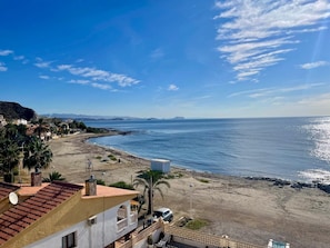 Vista costera con playa, edificios y cielo despejado.