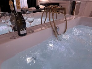 Zona de bar con una botella de vino Ast, copas y un taburete dorado.