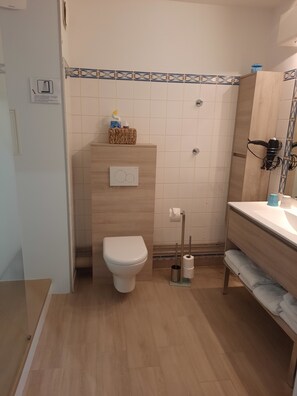 Ein Badezimmer mit Toilette, Waschbecken, Handtuchhalter und Duschbereich.