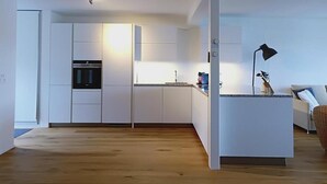 A modern kitchen with white cabinets, a built-in oven, and a small island with a lamp.