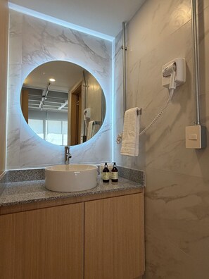 Une salle de bain avec un miroir rond, un lavabo et un porte-serviettes.