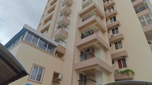 A high-rise building with multiple balconies, a sign indicating a hotel, and a covered entrance. - Tyche Stays (Thiruvananthapuram)