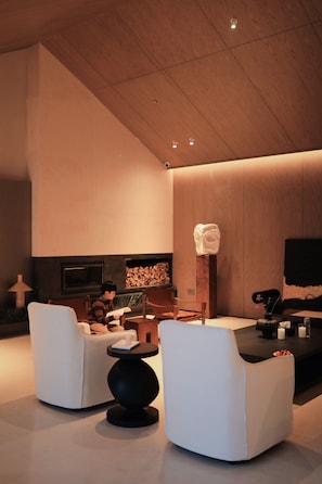 Ein modernes Interieur mit hohen Decken, Kamin und Fernseher.
