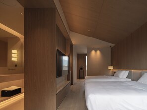 Habitación de hotel con una cama grande, televisor, espejo y baño.