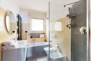 Een moderne badkamer met een badkuip, douche, toilet en een bidet.