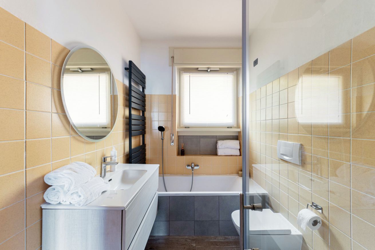 A modern bathroom with a sink, mirror, towel rack, shower, and toilet.