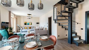 A modern dining area with a staircase and a sofa in the background. - Riflesso del Lago - by MyHomeInComo (Menaggio)