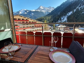 Un balcon avec une table dressée pour le dîner, offrant une vue sur un paysage montagneux avec des bâtiments en arrière-plan.