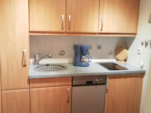A kitchen with wooden cabinets, a sink, a coffee maker, and a dishwasher. - Apartment for 2 persons, balcony, cable car included, pool and sauna in the house (Mittelberg)