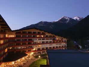 Un hôtel à plusieurs étages doté de balcons, d’un espace extérieur couvert et offrant une vue sur les montagnes.