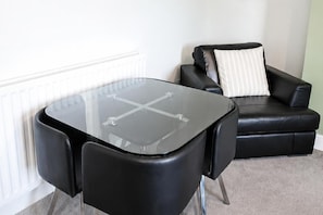 A modern living room with a glass-top table, black leather armchairs, and a white radiator. - House Sleeps 7 With Wifi (Gateshead)