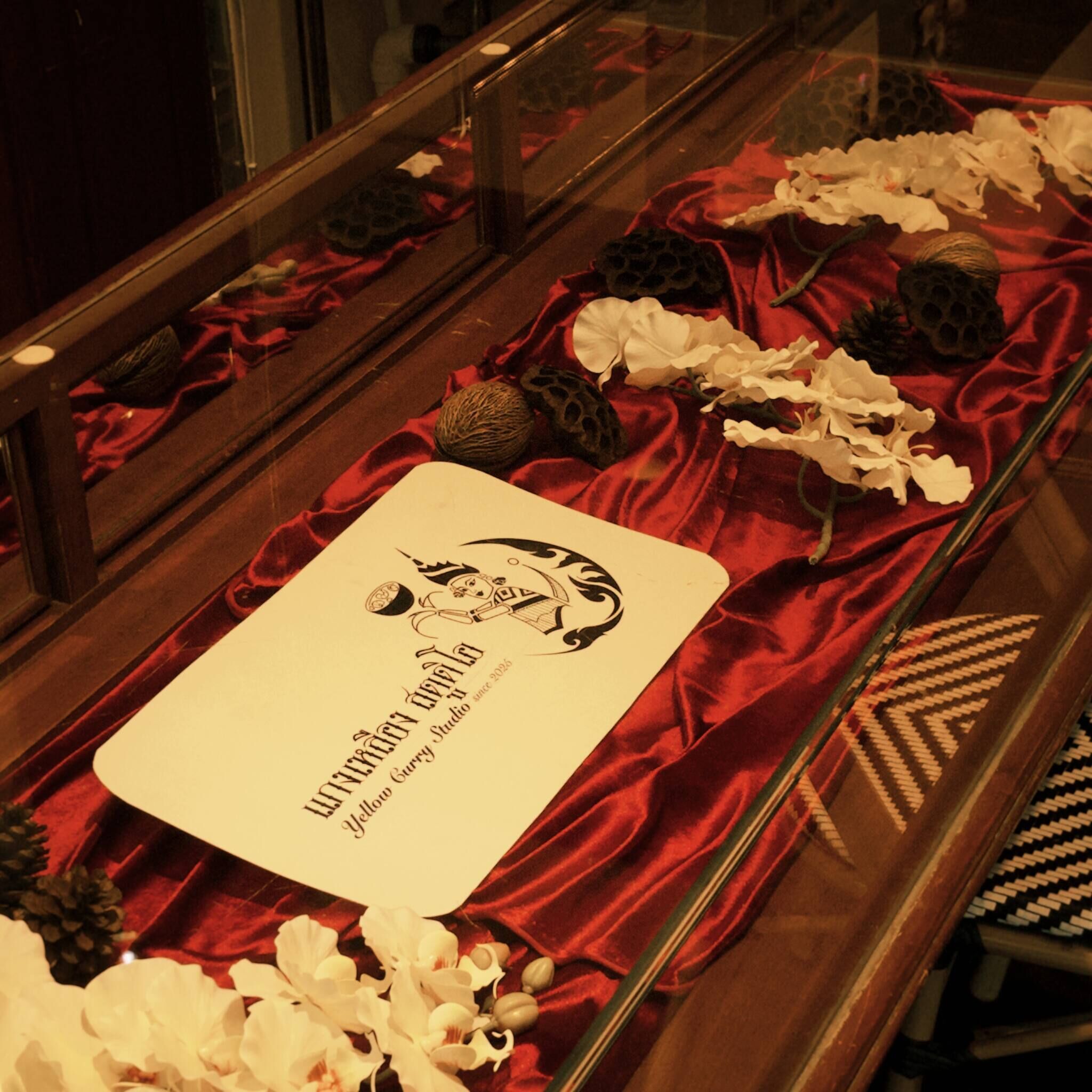 A menu with a logo and text, placed on a table with red fabric and decorative items.