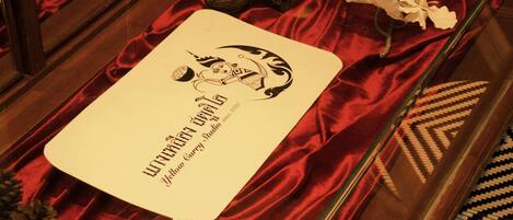 A menu with a logo and text, placed on a table with red fabric and decorative items.