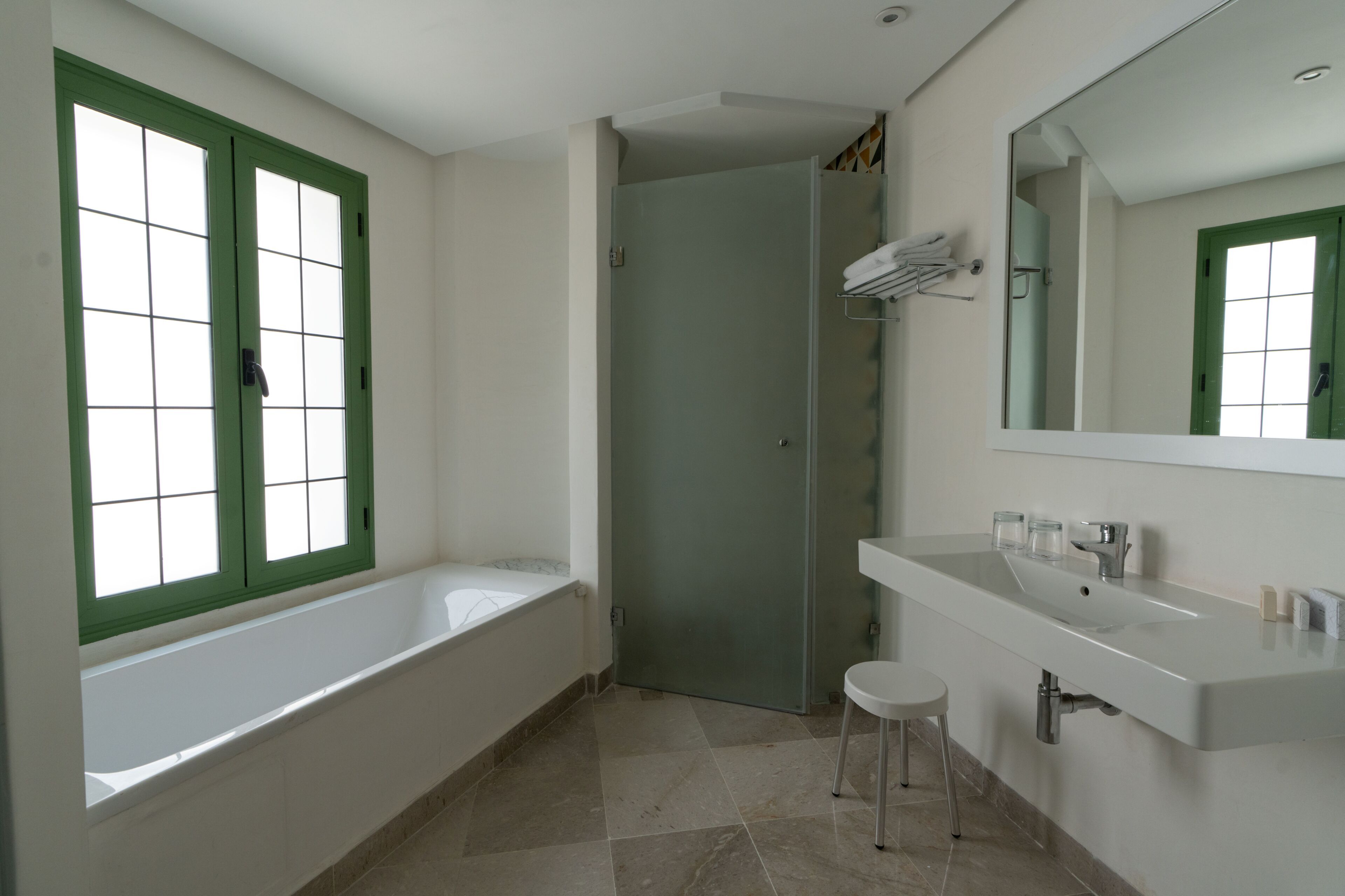 Casa de banho com banheira, pia, espelho e porta que dá para outro quarto.