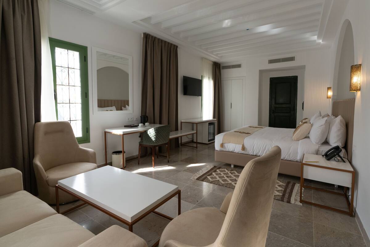 Una habitación de hotel con cama, escritorio, silla, sofá y televisión.
