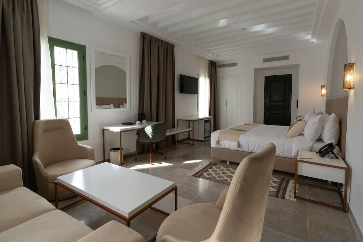 Una habitación de hotel con cama, escritorio, silla, sofá y televisión.