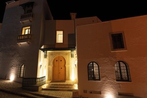 Un edificio con un'ampia porta in legno, un balcone e una piccola finestra.