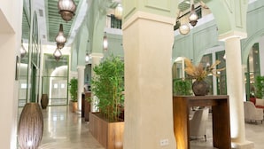 Un hall d’entrée spacieux, doté de hauts plafonds, de grandes colonnes et de plusieurs espaces aménagés pour s’asseoir.