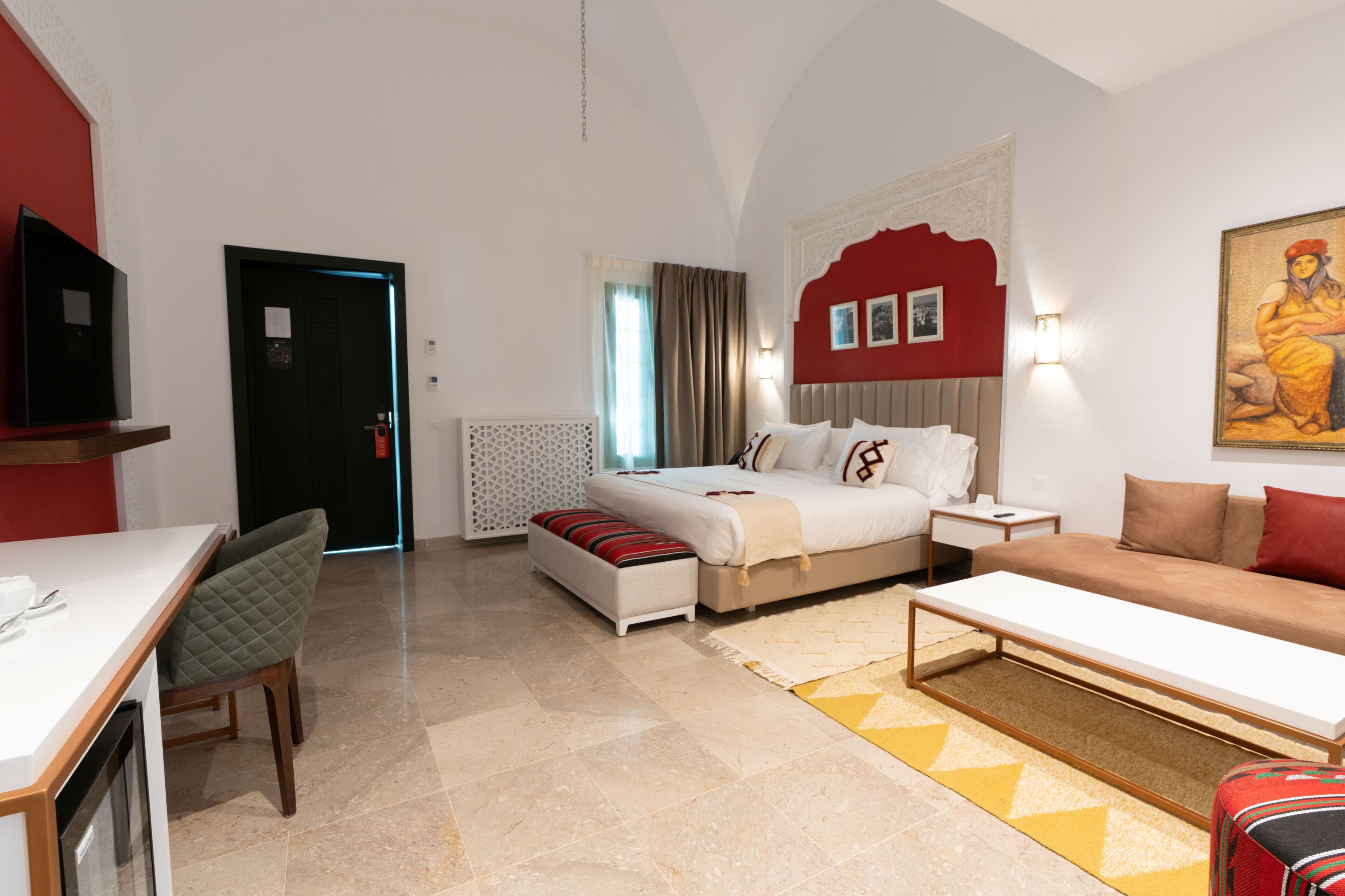 Una habitación de hotel con cama, sofá, mesa de comedor y televisor.