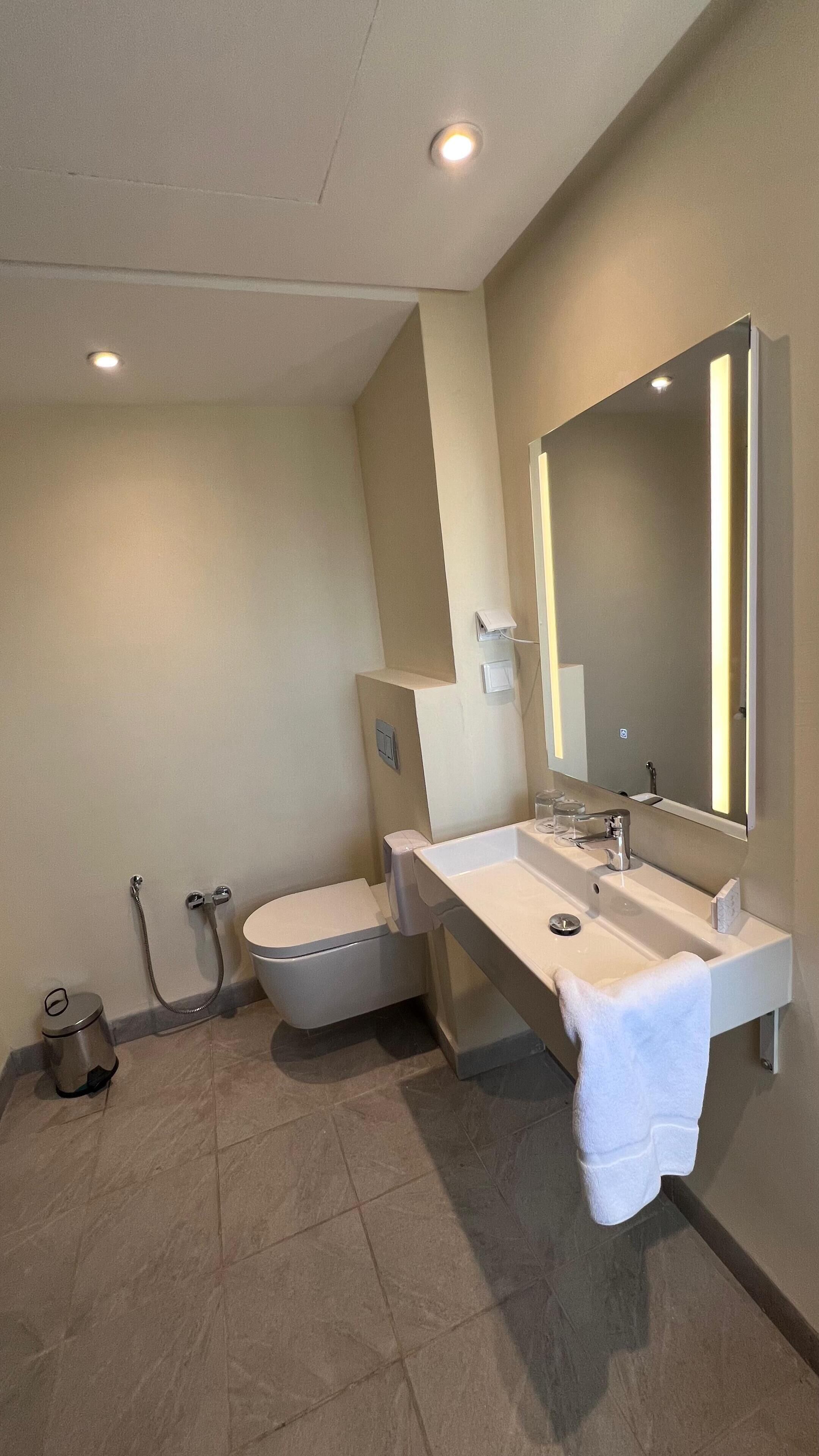 A modern bathroom with a toilet, bidet, and a sink with a towel hanging on the wall.